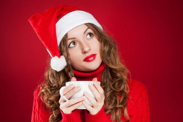Krásná brunetka v klobouk Santa Clause drží bílý hrnek Stock Obrázky