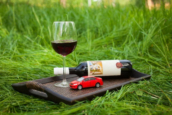 Νεκρή φύση με δίσκο, λίγο κόκκινο αυτοκίνητο, μπουκάλι, ποτήρι κρασί εξωτερι — Φωτογραφία Αρχείου