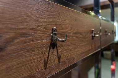 Soyunma odasındaki ahşap dolap paneline takılmış metal bir kancayı kapat.