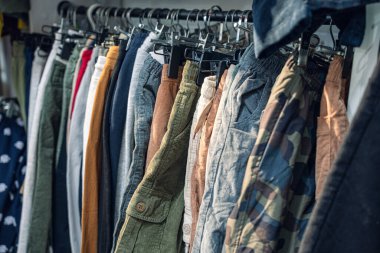 Perakende satış ortamında farklı renk ve stilleri sergileyen çeşitli pantolonlardan oluşan bir koleksiyon.