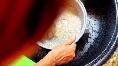 Bir kadın pilav tenceresinde pilavı duruluyor mutfak lavabosunda akan suyun altında. Yemek hazırlama sırasında çamaşır yıkama sürecinin yakın görüntüsü.