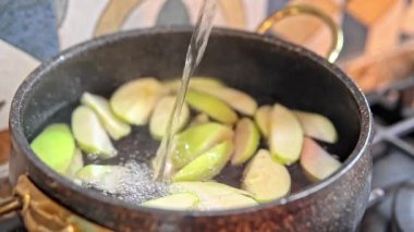 Ev yapımı komposto pişirirken vişne ve elma parçalarının yakın çekim görüntüsü. Mutfakta basit meyve hazırlama işlemi.