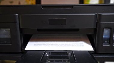 Beyaz kağıda döküman basan mürekkep püskürten yazıcının yakın görüntüsü. Ev ya da işyeri iş akışı sırasında çalışan ofis aygıtı.