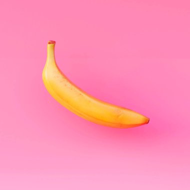 Pembe arka planda gölgesi olan pembe bir muz. Afişler, kartlar, el ilanları için arka plan resmi. Hazırla. Tropik meyveler. Egzotik meyveler.