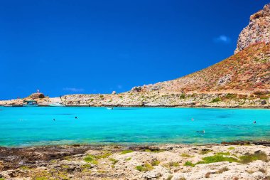 2019, 4 Haziran - GREECE, CRETE Adası, Balolar - Dağın tepesindeki şato ve altındaki plajdaki insanlar.