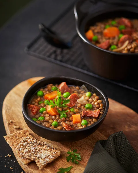 Traditional Spanish dish of lentil stew with chorizo and potatoes on a dark background. Selective focus. Mediterranean food recipe.