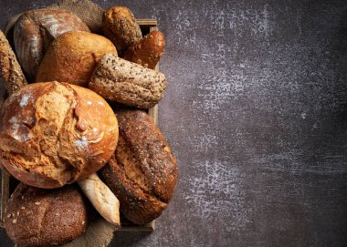 Farklı Ekmek Türleri olan arka plan, karanlık yüzeyde tahta bir kutuya konulmuş. Kapatın. Fırın konsepti. Metin için boş boşluk.