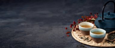 Koyu arkaplan pankartıyla mavi çaydanlıklı yeşil çay kompozisyonu. Geleneksel Çin çay seti, tören konsepti, seçici odaklanma. Boşluğu kopyala.