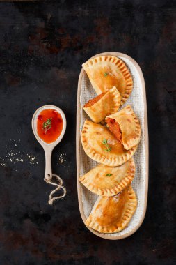 Tipik İspanyol börekleri, küçük orkinos ya da kızarmış etli turta, domates sosu, dolmalık biber. Karanlık arkaplan, kopyalama alanı. Akdeniz mutfağı kavramı.