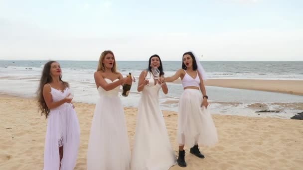 Quatro Meninas Vestidos Noiva Brancos Estão Praia Bebendo Vinho Espumante — Vídeo de Stock