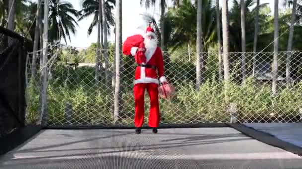 Санта Прыгает Батуте Пакетом Подарков Подарочной Коробкой Мальчик Костюме Санта — стоковое видео