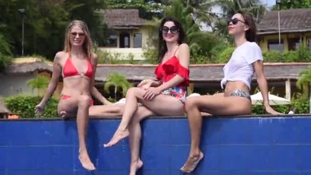 赤と白の水着のセクシーな若い女の子は暑い夏の晴れた日にスイミングプールに座っているとスプラッシュ水 豪華な熱帯リゾートの美しい女性の肖像 — ストック動画