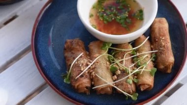 Geleneksel Vietnam mutfağı ve böreklerinin yakın çekimi. Kızarmış Asya gözlemesi. Vietnam börekleri mavi bir tabakta, soslu, beyaz bir masada.. 