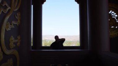 Kung fu ustası alıştırması yapıyor. Kung fu ustası büyük bir pencerede nefes alma pratiği yapıyor. Dövüş sanatlarında çalışan yaşlı bir adamın silueti.
