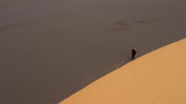 Siyah giyen yaşlı adam gün batımında kum tepelerinde kung fu yapıyor. Bir sürü kum, altın gün batımı ışığı. Spor eğitimi. Yakışıklı adam meditasyon yapıyor. Kum tepelerinin yanında yürür insan