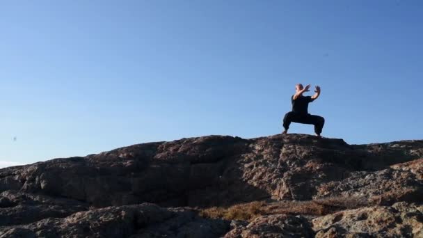 Een Man Het Zwart Staat Een Berg Een Krijger Pose — Stockvideo