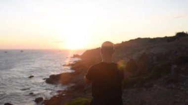 Sensei gün batımında deniz kenarında kung fu çalışıyor. Yaşlı adam gün batımında taş plajda kal ve egzersiz yap. 
