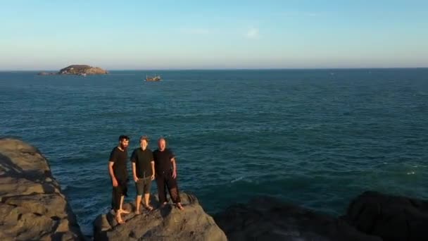 Trei Oameni Stau Stâncă Lângă Mare Apusul Soarelui Dronă Zboară — Videoclip de stoc