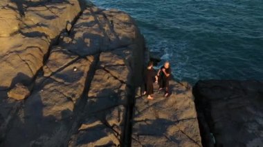 İki adam kung fu antrenmanı yaptı. Gün batımında deniz kenarındaki sporculara hava manzarası. Altın ışık, mavi gökyüzü ve okyanus. Erkekler kavga eder