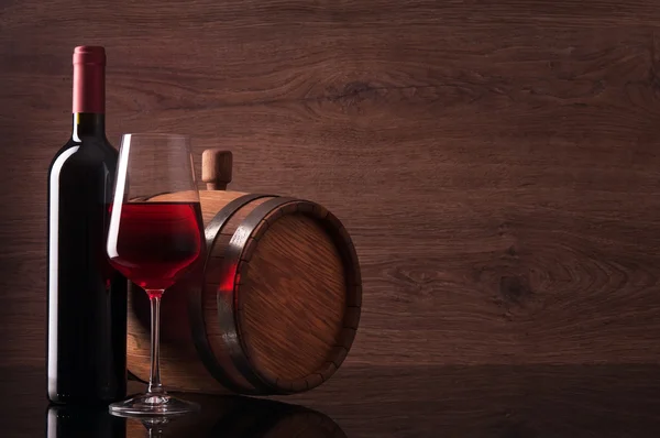 Fles rode wijn, glas en vat op houten achtergrond — Stockfoto