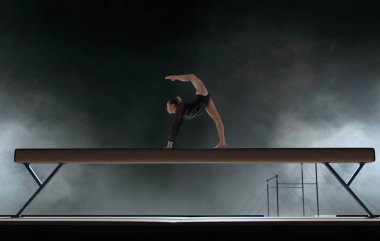 Profesyonel bir arenada kadın jimnastikçi karmaşık bir numara yapıyor.