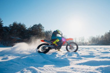 Donmuş bir nehrin buzunda motosiklet süren bir motosiklet sürücüsü.