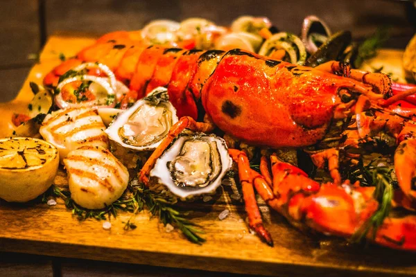 a seafood platter with lobster, scallops, mussels, clams and oysters served on a wooden block
