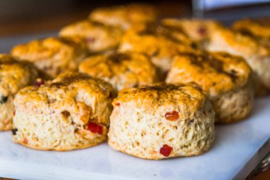Kurutulmuş meyve ve kuru üzümlü çörekler beyaz bir tahtada servis edilir.