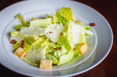 Bir tabak salata, marul, kızarmış ekmek ve pastırma.