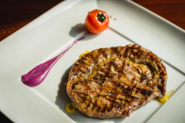 Izgara biftekle servis edilen ızgara domates ve taro püresi.