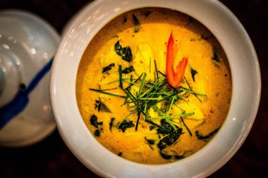 Tayland yeşili köri, tavuk ve otlarla süslenmiş ve beyaz bir kasede servis ediliyor.