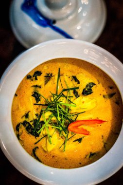 Tayland yeşili köri, tavuk ve otlarla süslenmiş ve beyaz bir kasede servis ediliyor.