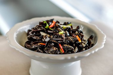 Beyaz bir porselen tabakta servis edilen korunmuş sirkeli bir mantar aperatifi.