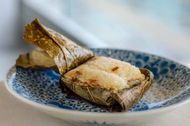 Güzel bir porselen tabakta sunulan nilüfer yapraklarına sarılı Glutinous Rice 'ın ana yemeği.