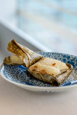 Güzel bir porselen tabakta sunulan nilüfer yapraklarına sarılı Glutinous Rice 'ın ana yemeği.