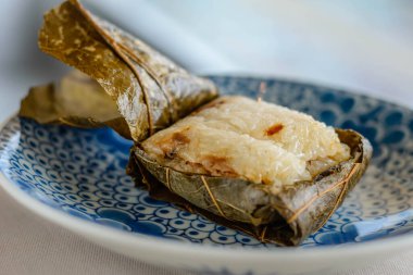 Güzel bir porselen tabakta sunulan nilüfer yapraklarına sarılı Glutinous Rice 'ın ana yemeği.