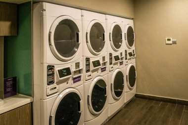 Çamaşır makinelerinin üst sıralarında bir sıra kurutucu olan bir çamaşırhane.