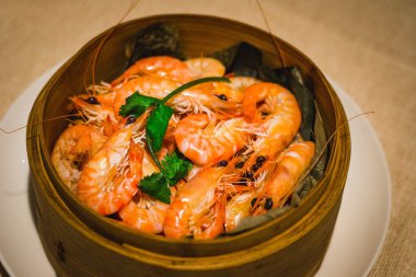 Buharlı nehir karidesleri ve maydanozla süslenmiş bir buhar sepetine.