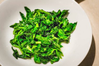 yeşil sebzeler Çin usulü kızartılmış ve beyaz tabakta servis ediliyor.