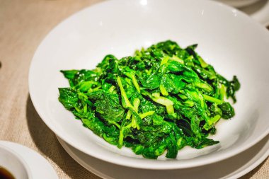 yeşil sebzeler Çin usulü kızartılmış ve beyaz tabakta servis ediliyor.