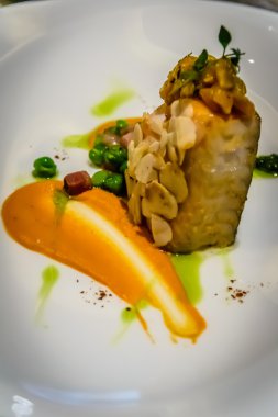 Pan katılaşmış siyah morina dolmalık biber ve fındık mus, badem, biber ve yeşil bezelye ile servis edilir