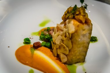 Pan katılaşmış siyah morina dolmalık biber ve fındık mus, badem, biber ve yeşil bezelye ile servis edilir