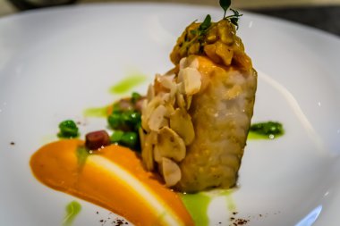 Pan katılaşmış siyah morina dolmalık biber ve fındık mus, badem, biber ve yeşil bezelye ile servis edilir