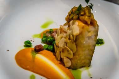 Pan katılaşmış siyah morina dolmalık biber ve fındık mus, badem, biber ve yeşil bezelye ile servis edilir