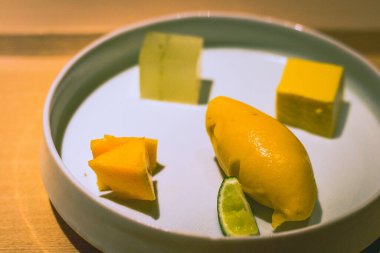 Tatlı tabağında enfes bir mango şerbeti, taze mango küpleri, mango jölesi ve yuzu jölesi var.