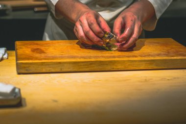 Japon omakaz şefinin elleri omakase tezgahında suşi hazırlıyor.