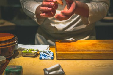 Japon omakaz şefinin elleri omakase tezgahında suşi hazırlıyor.