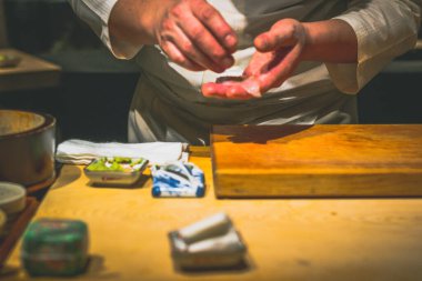 Japon omakaz şefinin elleri omakase tezgahında suşi hazırlıyor.