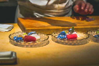 Japon omakaz şefinin elleri tezgahta çiğ balık hazırlıyor.