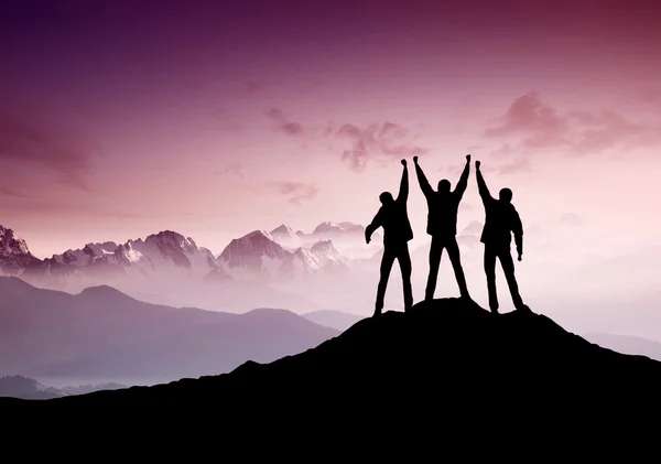 Silhouettes of team on mountain peak — Stock Photo, Image